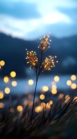 Delicate grass silhouette against blurred evening lights creating magical bokeh effect, moody blue twilight atmosphere with glowing golden orbs in background.