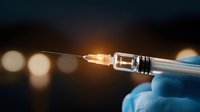 Medical syringe with glowing liquid and needle against dark background with bokeh lights, held by hand in blue surgical glove.