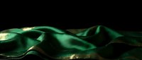 Abstract green silk fabric waves flowing elegantly against black background creating luxurious textile motion with smooth curves and dramatic lighting effects.