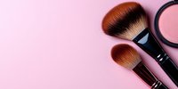 Professional makeup brushes and cosmetic powder compact on pink background with copy space, minimal beauty concept for cosmetics advertising.