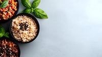 Cooked brown and white rice in black bowls garnished with basil leaves and spices on light gray background, top view with copy space for menu design.