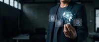 Businessman holding glowing light bulb with digital security icons and global network connections in modern office environment for technology concepts.