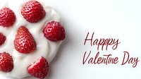 Fresh ripe raspberries arranged in heart shape on white cream background with romantic Valentine Day greeting text in red calligraphy lettering.