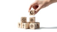 Hand placing wooden cube with esoteric symbols on pyramid stack isolated on white background for spiritual design concepts.