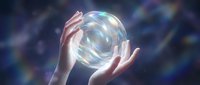 Hands holding glowing translucent sphere with rainbow light effects against cosmic background for spiritual energy healing meditation concepts.