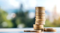 Stack of golden coins on reflective surface against blurred natural background showing financial growth and investment concept. Money saving arrangement.