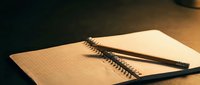Open spiral notebook with blank pages and black pen on wooden desk surface, suitable for writing, planning, education, and office work.