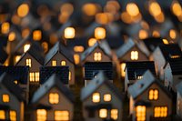Miniature glowing houses creating cozy evening atmosphere with warm window lights and soft bokeh effect in background, festive holiday decorative display.