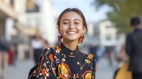 Young Hispanic woman smiling confidently on urban street wearing floral dress, perfect for lifestyle and fashion marketing campaigns.