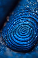 Mesmerizing spiral pattern in deep blue metallic pigment with sparkling glitter effect, captured in extreme macro photography. Suitable for abstract art and design projects.