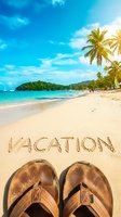 Flip flops on a sunny tropical beach with vacation written in sand, turquoise sea and palm trees in background, summer travel concept.