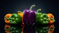 Colorful bell peppers arranged on a reflective dark surface, showcasing vibrant orange, green, and purple varieties in a studio setting.