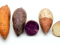 Colorful sweet potato varieties including orange, purple and white types with cross-section showing vibrant flesh isolated on white background for cooking.