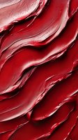 Luxurious red lipstick texture with smooth wavy strokes and glossy surface creates abstract pattern. Macro cosmetic background for beauty industry and makeup artistry.