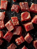 Fresh raw tuna cubes with sea salt crystals on dark background, close up view. Premium seafood preparation for poke bowl, tartare or sashimi.