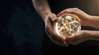 Two hands gently holding glowing light bulb with warm filament against dark background symbolizing innovation, creativity and collaborative teamwork.