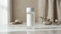 White cosmetic bottle with pump dispenser on marble surface surrounded by natural stones and dried eucalyptus branches in minimalist spa setting.