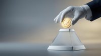 Hand in white glove placing golden coin into silver pyramid-shaped container, representing wealth accumulation, investment strategy, and financial growth for business concepts.