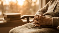 Senior man hands folded peacefully in warm golden sunlight streaming through window creating serene contemplative moment of rest and reflection.