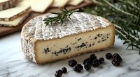 Artisanal blue cheese wedge with white rind on marble surface, garnished with fresh rosemary sprigs and dried blueberries, showcasing gourmet food styling.