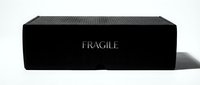 Black cardboard shipping box with fragile warning text and ribbed texture, suitable for packaging, logistics, delivery services, e-commerce, and product protection concepts.