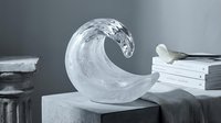 Crystal glass wave sculpture on concrete pedestal, elegant home decor accent with books and flower in soft gray studio setting.