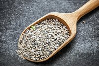 Nutritious chia seeds in wooden spoon on dark stone background, macro view of healthy superfood rich in omega-3 fatty acids and fiber.