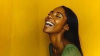 Young African American woman with bright genuine smile and long straight black hair laughing against vibrant yellow background, expressing pure joy and happiness.