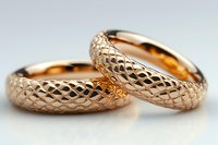 Rose gold wedding bands featuring intricate diamond-cut pattern surface with luxurious textured finish on light background, symbolizing eternal commitment.