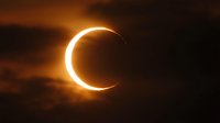 Dramatic solar eclipse with glowing corona ring against dark cloudy sky creating stunning celestial phenomenon for astronomy and space education materials.