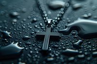 Silver cross pendant necklace on dark wet surface with water drops creating dramatic atmosphere. Religious jewelry macro photography.