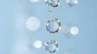 Clear water bubbles floating against soft blue background with bokeh light effects for spa wellness and purity concepts.