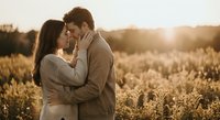 Romantic couple embracing in golden wheat field during sunset, intimate moment with warm sunlight creating dreamy atmosphere for love and relationship concepts.