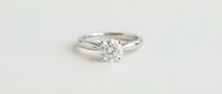Classic solitaire diamond engagement ring with round brilliant cut stone in white gold setting on neutral background for jewelry and wedding concepts.