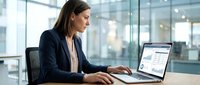 Professional businesswoman working on laptop in modern office environment with glass walls and natural lighting for corporate presentations.