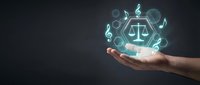 Legal services and justice concept with glowing scales icon held in open hand against dark background, representing law, compliance, and professional counsel.