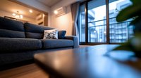 Modern living room interior with gray sofa, wooden floor and large window offering city views. Cozy home atmosphere with soft evening lighting and minimalist decor.
