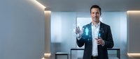 Confident Caucasian businessman in suit interacting with glowing holographic human figure interface in modern futuristic office environment.