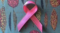 Pink awareness ribbon on decorative floral pattern background symbolizing breast cancer support and solidarity in healthcare advocacy movement.