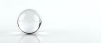 Clear glass sphere on white reflective surface with soft lighting and minimalist composition for modern design projects.