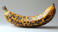 Overripe banana with brown spots on neutral background for healthy eating, nutrition education, food waste awareness and organic produce concepts.