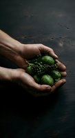 Male hands holding fresh green berries and small fruits on dark textured surface, suitable for organic food, agriculture, and harvest concepts.