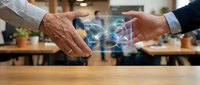 Two business professionals exchanging digital data through holographic interface technology in modern office workspace for corporate communication solutions.