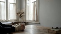 Cozy reading corner with open book and dried flowers by sunny windows in minimalist home interior for relaxation and leisure lifestyle concepts.