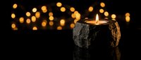 Rustic wooden candle holder with flickering flame creates warm ambiance against bokeh lights background for cozy home decor and relaxation atmosphere.