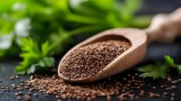 Fresh organic chia seeds in wooden scoop scattered on dark background with green herbs, healthy superfood rich in omega-3 fatty acids and fiber.