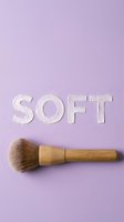 Soft makeup brush with wooden handle on lavender background with embossed text, ideal for cosmetics, beauty product marketing, skincare tutorials, and salon promotional materials.