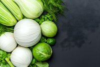 Fresh white and green fennel bulbs with brussels sprouts and leafy herbs arranged on dark background, top view with copy space for food photography.