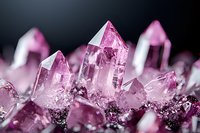 Pink quartz crystal formation with multiple pointed peaks against dark background, macro photography showing natural mineral structure and light reflection.