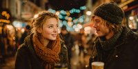 Young couple enjoying romantic winter evening date at outdoor market with warm bokeh lights and cozy atmosphere for holiday celebration and togetherness.